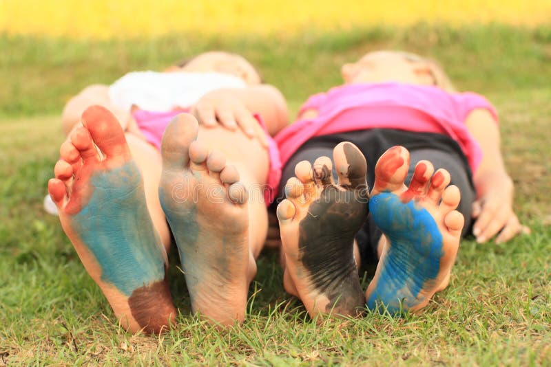 Bare feet of a smiling kids - girls with soles painted on blue, red and black. Bare feet of a smiling kids - girls with soles painted on blue, red and black