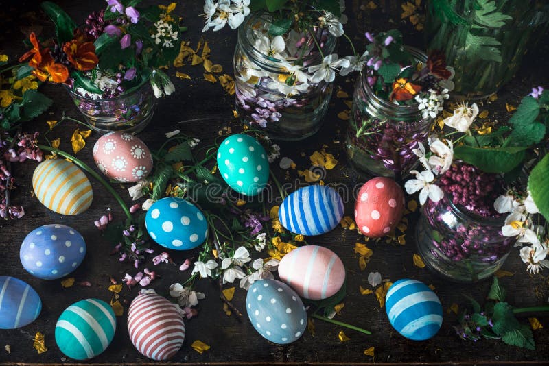 Malowniczy bukiety kolorowi wiosna kwiaty w szklanych waz butelkach i kolorowych handmade farby Easter jajkach na zmroku drewnian fotografia royalty free Malowniczy bukiety kolorowi wiosna kwiaty w szklanych waz butelkach i kolorowych handmade farby Easter jajkach na zmroku drewnian fotografia royalty free