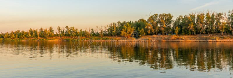 Malowniczy letni panoramiczny krajobraz z brzegiem rzeki o zachodzie słońca. spokojne odbicie rzeki w wodzie. wspaniała natura zdjęcia royalty free