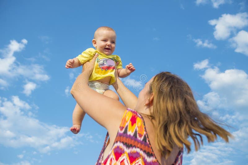 Mam tilt een kind in zijn armen tegen de lucht Veel plezier buitenshuis, liefde en geluk concept stock foto Mam tilt een kind in zijn armen tegen de lucht Veel plezier buitenshuis, liefde en geluk concept stock foto