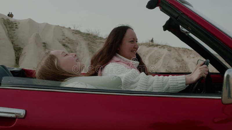 Mama córka cieszy się wycieczką samochodem na naturze uśmiechając się siedząc w vintage cabriolet car.