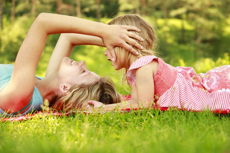 Mama and her little daughter lie on the grass