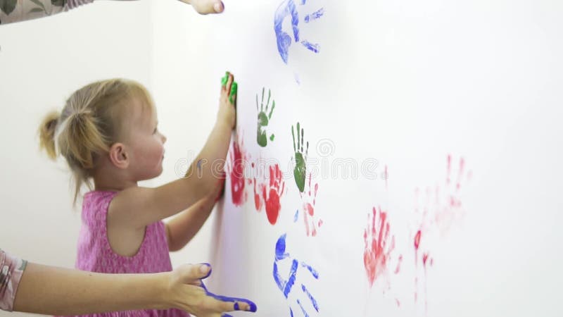 Mama i córka robią odciski palców za pomocą farb na białym papierze.