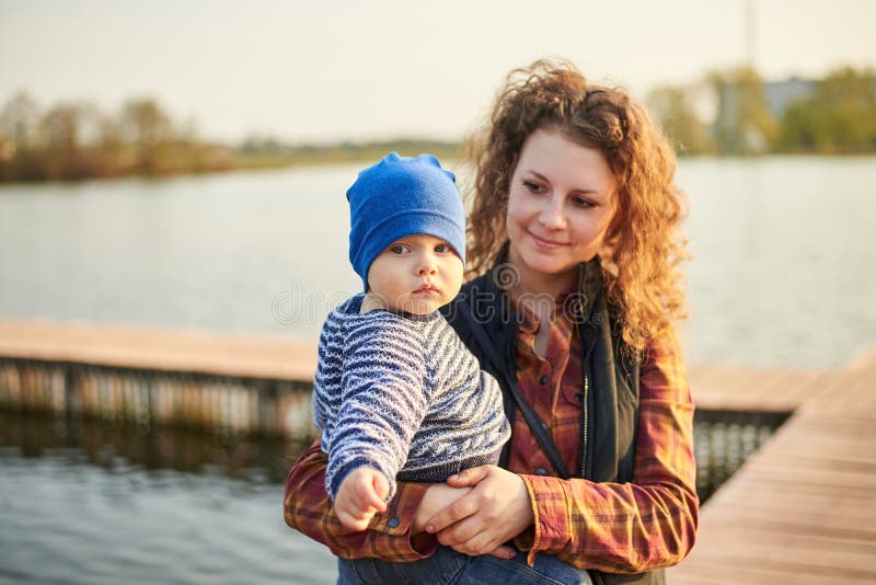 Mama stojaki przy molem na rzece z jej synem Mam spojrzenia przy jej uśmiechami i dzieckiem zdjęcia royalty free Mama stojaki przy molem na rzece z jej synem Mam spojrzenia przy jej uśmiechami i dzieckiem zdjęcia royalty free