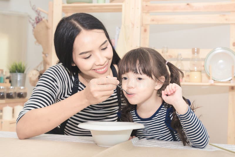 Maman asiatique alimentant le petit déjeuner sain à sa fille mignonne photo libre de droits Maman asiatique alimentant le petit déjeuner sain à sa fille mignonne photo libre de droits