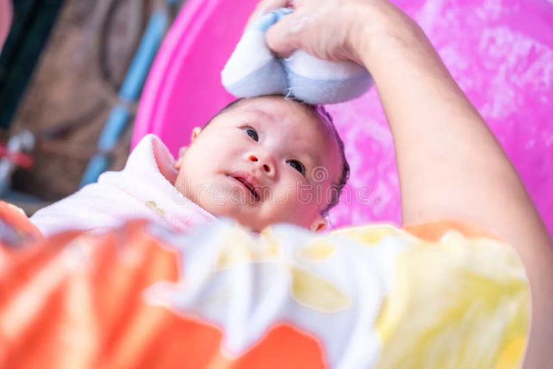 maman asiatique douche bébé pour nettoyer la saleté donner à l'enfant dans  le bain récipient