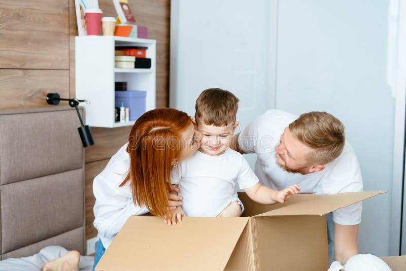 Maman de papa et petit jeu de fils dans la chambre à coucher avec les boîtes de papier photo stock Maman de papa et petit jeu de fils dans la chambre à coucher avec les boîtes de papier photo stock