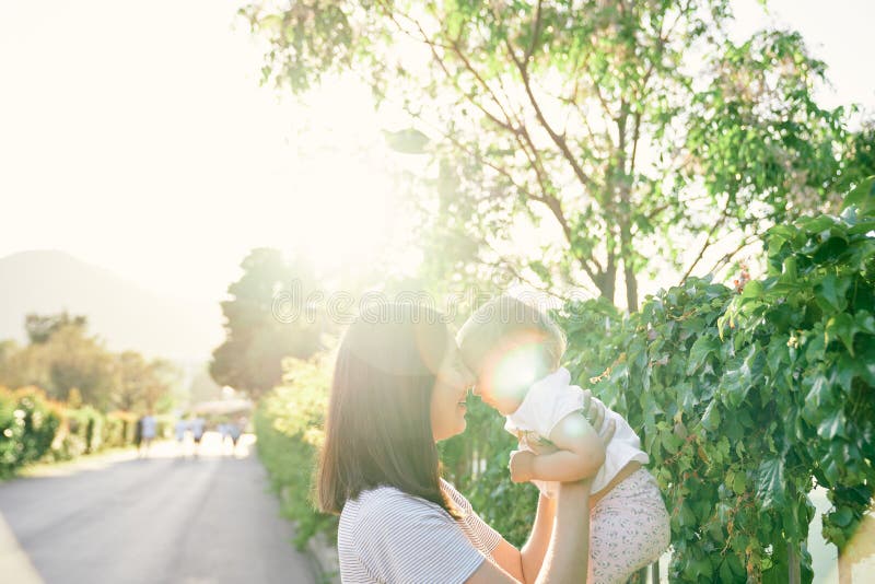 Mom lifted a little girl in her arms at the fence, entwined with ivy. High quality photo. Mom lifted a little girl in her arms at the fence, entwined with ivy. High quality photo