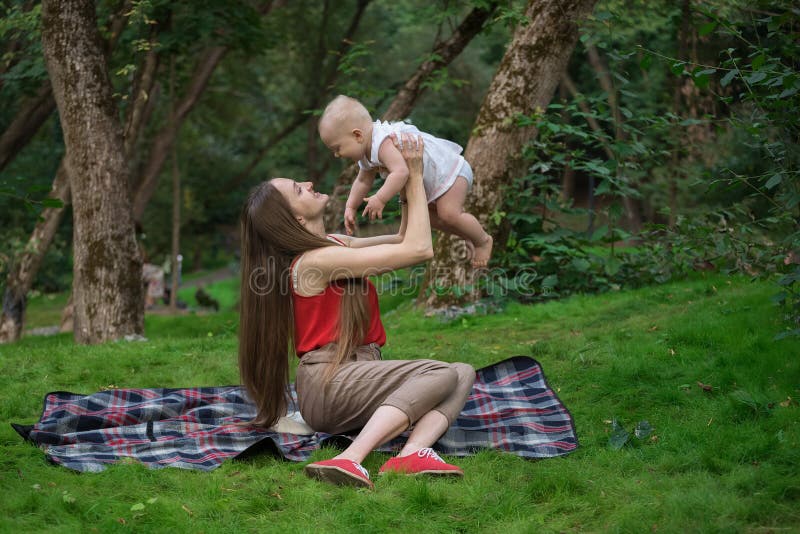 Mom lifted up the baby in her arms. Family picnic on the nature. Carefree maternity. Mom lifted up the baby in her arms. Family picnic on the nature. Carefree maternity.