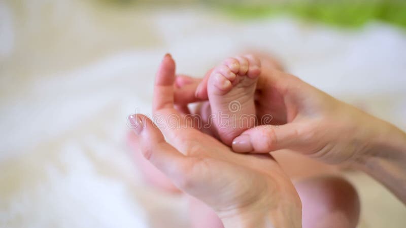 Maman touchant doucement les pieds des bébés. femme fait un massage tactile des pieds pour bébé. fermer. banque de vidéos