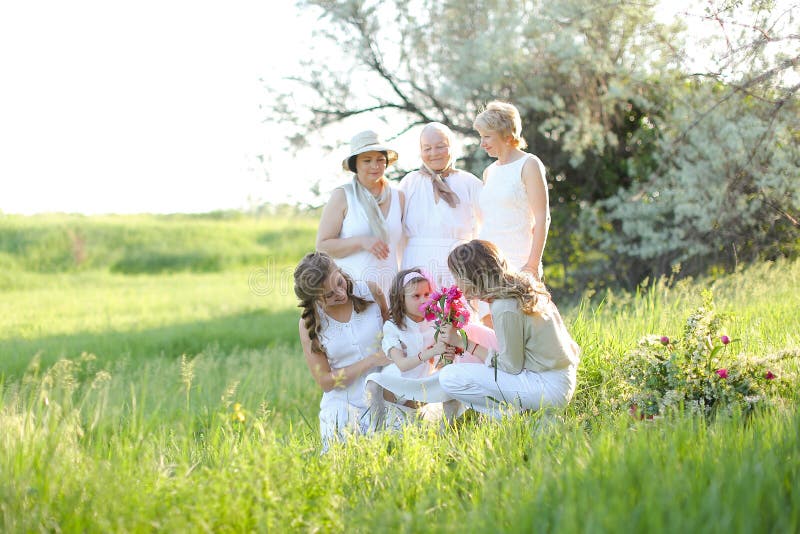 Mamie européenne embrassant des filles et des petites-filles vêtues de blanc à l'extérieur. photo stock