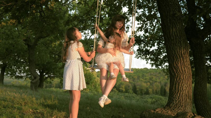Mamma cammina con i bambini e nuota in un'altalena nel parco. il concetto di famiglia felice. sogno di volare. concetto video d archivio
