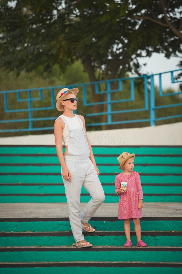 Mamma dei pantaloni a vita bassa in cappello di paglia con la figlia a piedi nudi Stile del film fotografia stock Mamma dei pantaloni a vita bassa in cappello di paglia con la figlia a piedi nudi Stile del film fotografia stock