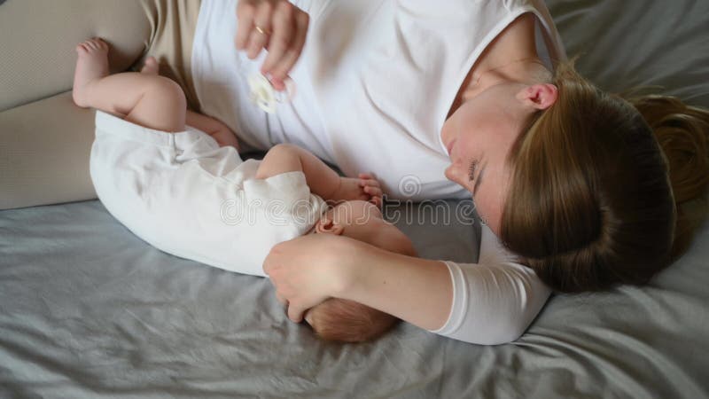 Mamma e bambino stanno insieme sulla madre che abbraccia il bambino così che si senta al sicuro. madre premurosa rimuove il pacifi stock footage