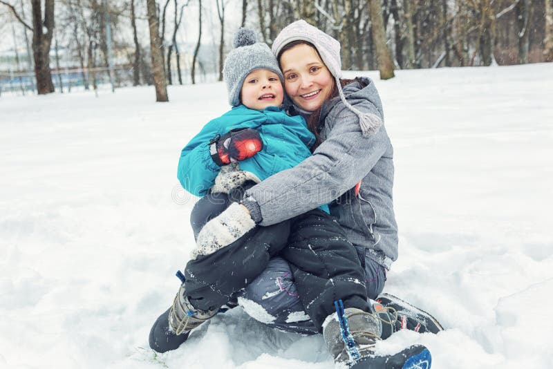 Mamma e piccolo figlio che giocano nella neve immagine stock Mamma e piccolo figlio che giocano nella neve immagine stock