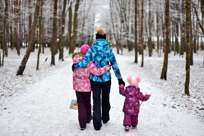 Mamma en haar dochters voor een gang in het hout op de sneeuwwinter stock foto's Mamma en haar dochters voor een gang in het hout op de sneeuwwinter stock foto's