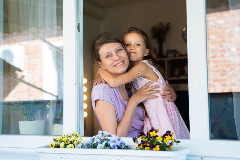 Mamma kvinna med dotters förskolebarn titta ut genom fönstret arkivfoto