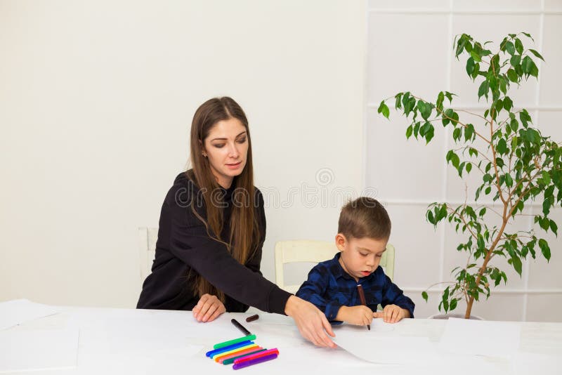 Mamma med en liten pojke lär sig att rita markörer royaltyfria foton Mamma med en liten pojke lär sig att rita markörer royaltyfria foton
