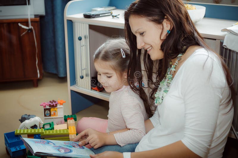 Mamma och dotter som läser en ansedd mycket intressant bok arkivfoton Mamma och dotter som läser en ansedd mycket intressant bok arkivfoton