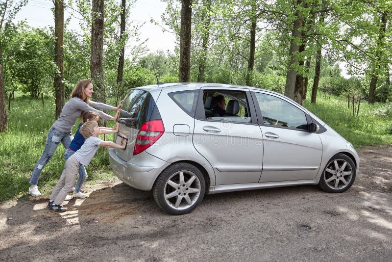 Mamma, zoon en dochter die een defecte auto duwen stock afbeelding Mamma, zoon en dochter die een defecte auto duwen stock afbeelding