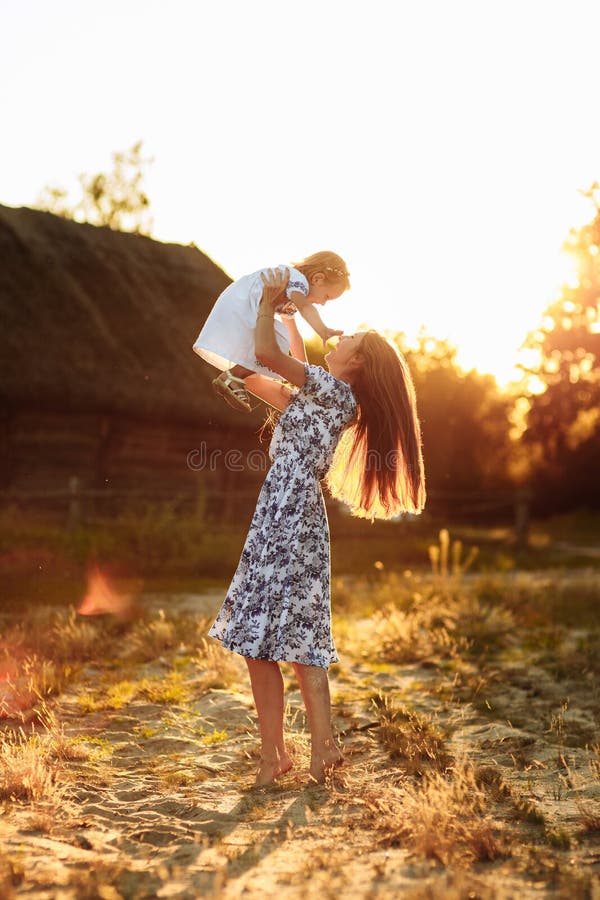 Mammaspelen met haar weinig dochter, gelukkige vrouw die met meisjesdochter geniet van die haar houdt omhoog opheffend in haar wa royalty-vrije stock fotografie Mammaspelen met haar weinig dochter, gelukkige vrouw die met meisjesdochter geniet van die haar houdt omhoog opheffend in haar wa royalty-vrije stock fotografie