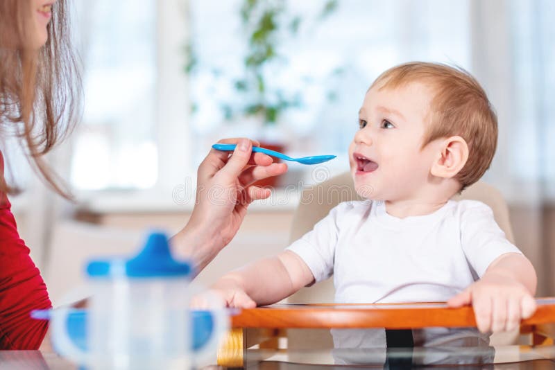 Mamy dziecka mienia żywieniowa ręka z łyżką owsianka Emocje dziecko podczas gdy jedzący zdrowego jedzenie