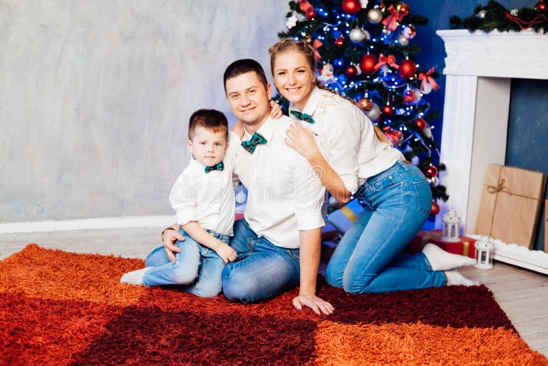 Mamá padre e hijo abren Regalos Navidad Año Nuevo árbol vacaciones de invierno Garland foto de archivo