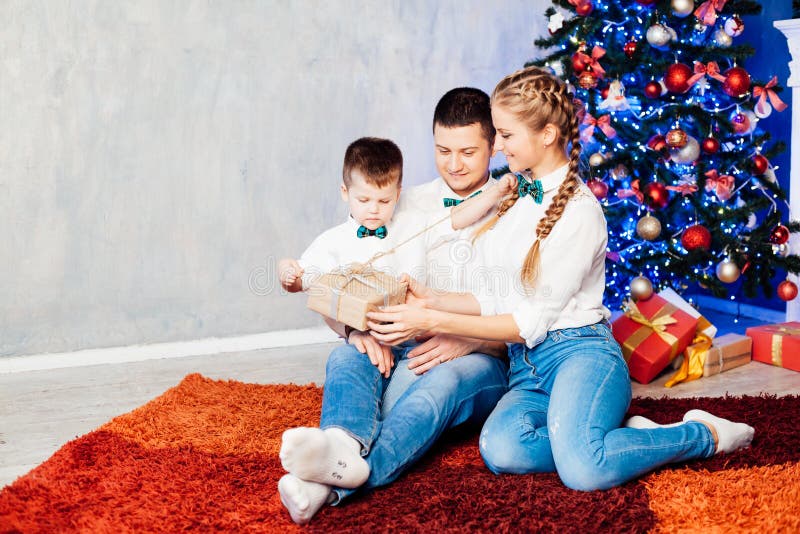 Mamá padre e hijo abren Regalos Navidad Año Nuevo árbol vacaciones de invierno Garland foto de archivo libre de regalías