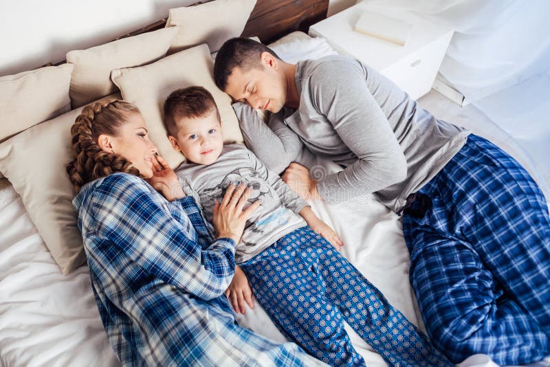 Mamá papá e hijo mienten en la cama en el sueño de casa fotografía de archivo