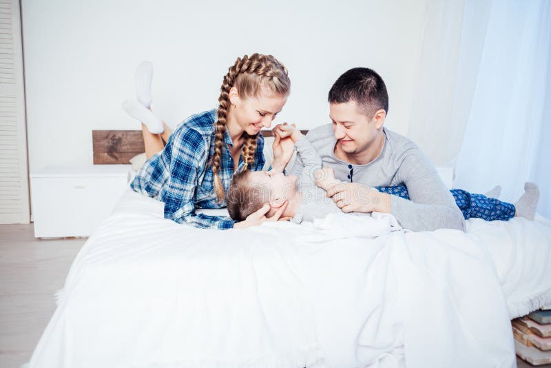 Mamá, papá e hijo pequeño duermen en la cama en el dormitorio imagen de archivo libre de regalías