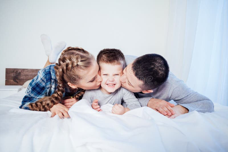 Mamá, papá e hijo pequeño duermen en la cama en el dormitorio fotos de archivo libres de regalías