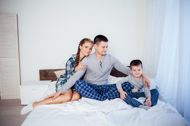 Mamá, papá e hijo pequeño duermen en la cama en el dormitorio foto de archivo