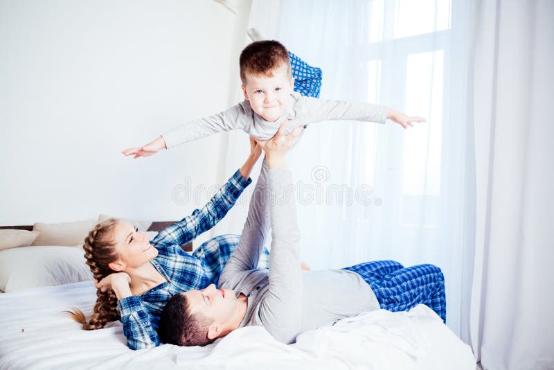 Mamá, papá e hijo pequeño duermen en la cama en el dormitorio imagen de archivo