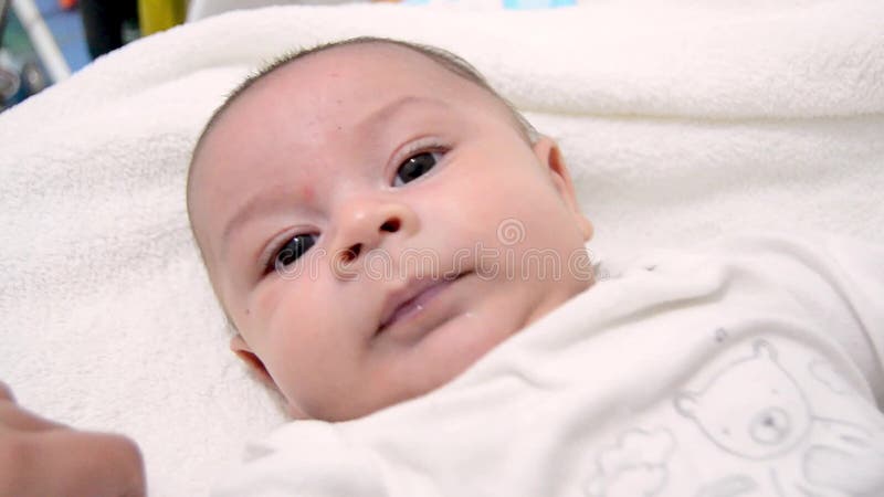 Mamá que abraza al bebé lindo de los meses del árbol vestido en el traje blanco del cuerpo