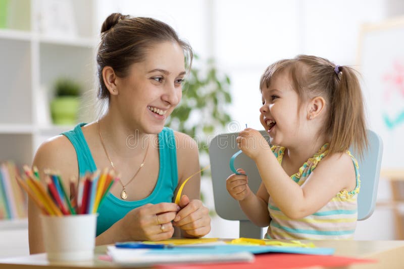 Mamá ayudando a su hijo a trabajar con papel de colores imagen de archivo