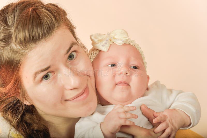 Mamá sostiene al bebé en sus brazos y posa para la cámara en el estudio, el concepto de amor y unidad y cuidado de los seres qu foto de archivo libre de regalías Mamá sostiene al bebé en sus brazos y posa para la cámara en el estudio, el concepto de amor y unidad y cuidado de los seres qu foto de archivo libre de regalías