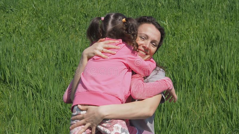 A mamã abraça crianças na natureza Mulher com meninas em um parque na grama verde Família que abraça no gramado