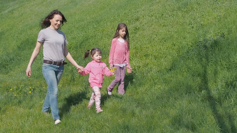 A mamã e a filha estão andando no parque Família fora em um dia ensolarado Crianças com mãe fora no verão