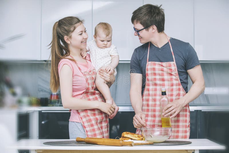 Mamã, paizinho e bebê pequeno cozinhando bolos na cozinha junto a imagens de stock Mamã, paizinho e bebê pequeno cozinhando bolos na cozinha junto a imagens de stock
