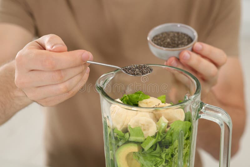 Man Adding Chia Seeds into Blender with Ingredients for Smoothie