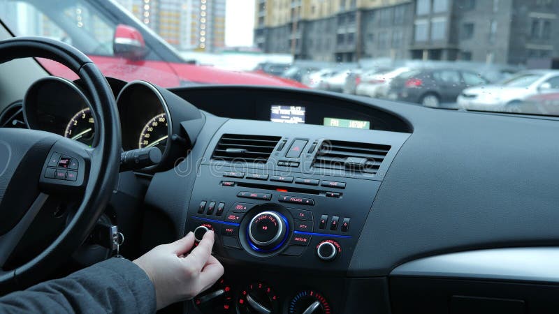 Un uomo di regola un ricevitore radio e regola il volume della musica in auto.