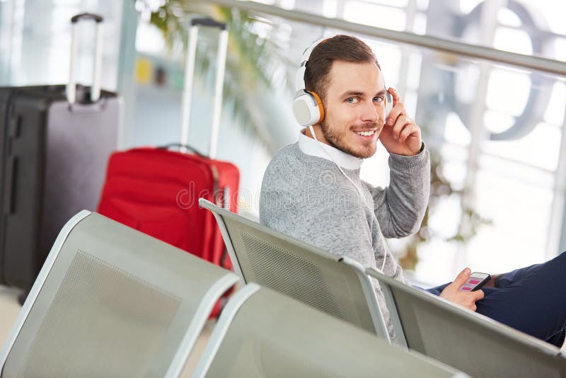 Man in the airport waits for flight and listens to music