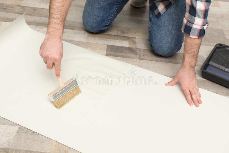 A Man Applies Wallpaper Glue With Brush For Wallpapering Repair Of