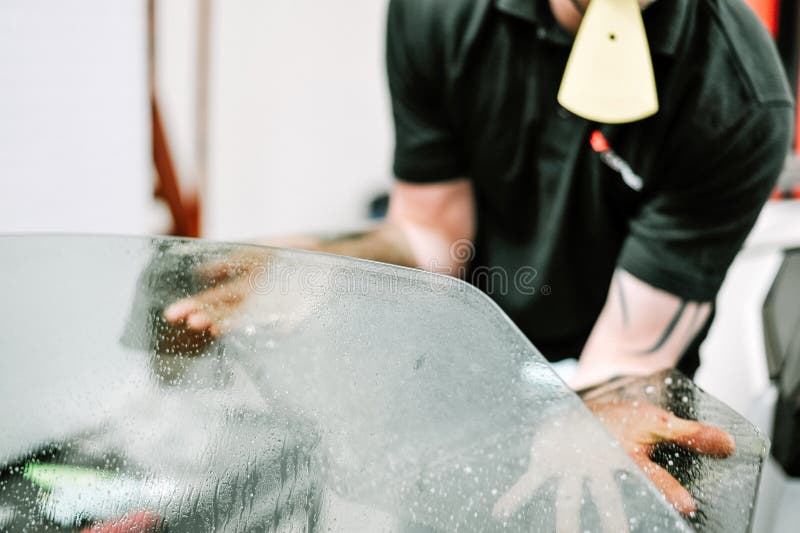 Man applying window tinting film on a car stock photos Man applying window tinting film on a car stock photos