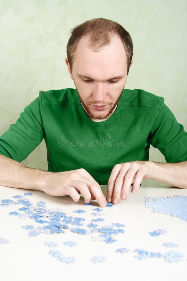 Man assembling blue puzzle pieces