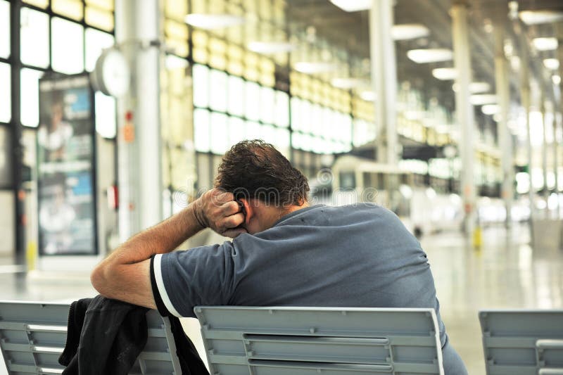 Man att sova på en bänk i järnvägsstationen fotografering för bildbyråer Man att sova på en bänk i järnvägsstationen fotografering för bildbyråer
