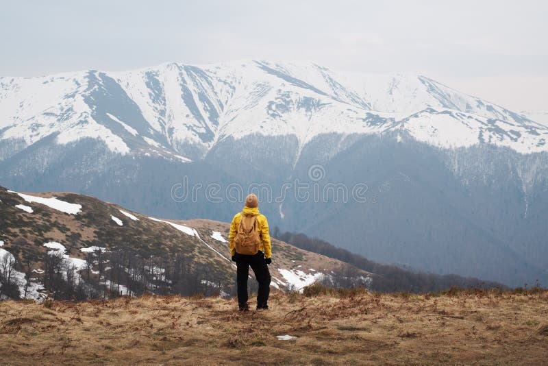 Man with backpack in spring snowy mountains