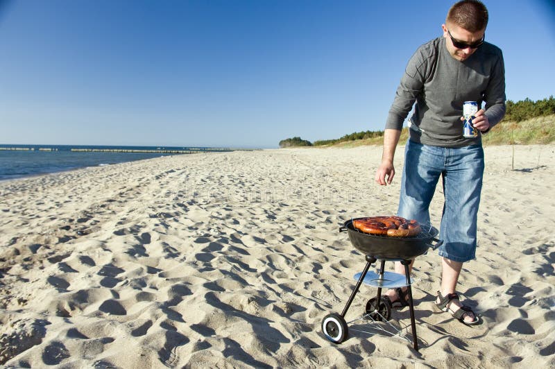 Man and barbecue on beach stock image. Image of holding 5142917