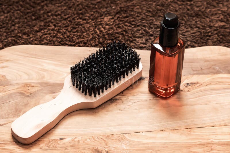 Man beard grooming items, wooden comb and oil on a wooden board and brown towel.