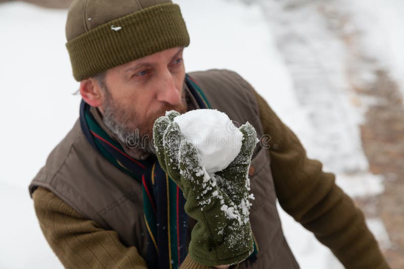 Man with beard in hat throwing snowballs in yard stock images